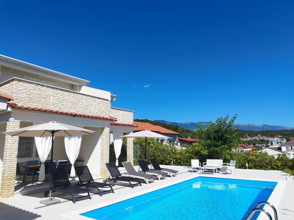 a villa with a swimming pool and patio furniture at Holiday house Altea , Barbat on the Island Rab in Rab