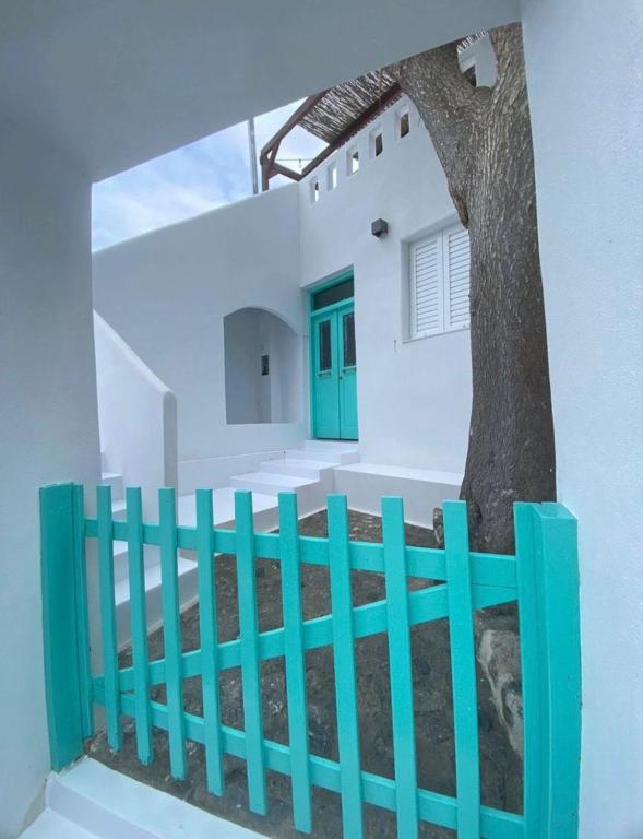 ein blauer Zaun vor einem Haus mit einem Baum in der Unterkunft Villa Benjamin in Mílatos