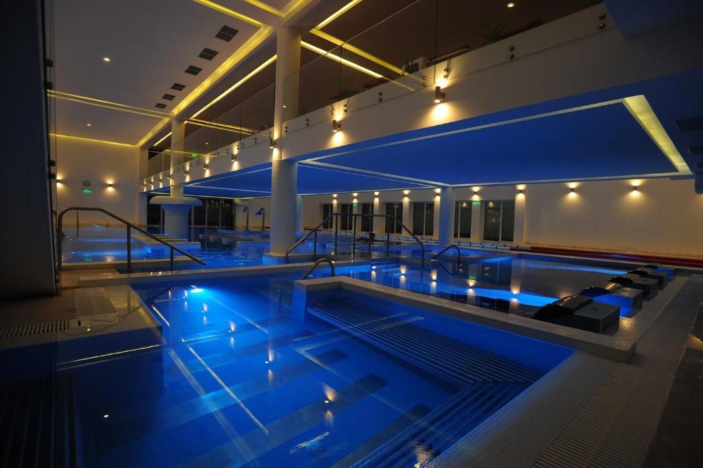 Aqvatonic Hotel - Steaua de Mare في إيفوري نورد: حمام سباحة كبير مع أضواء زرقاء في مبنى
