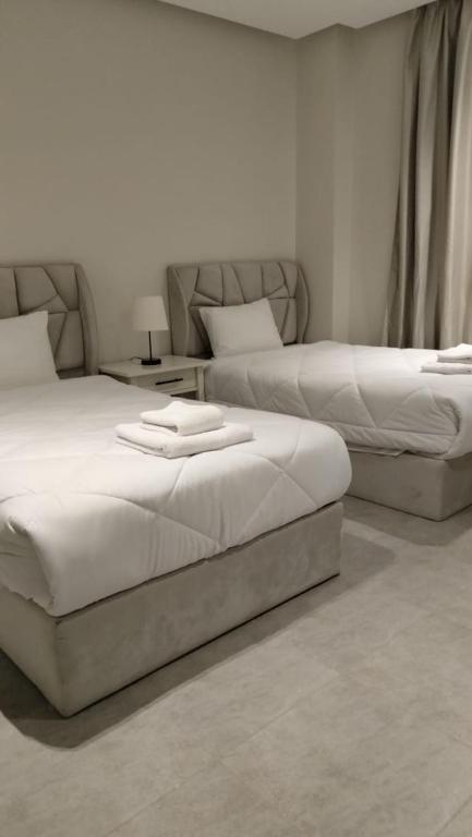 two beds sitting in a room with at Lurret Hotel in Qaryat at Ta‘mīr as Siyāḩīyah