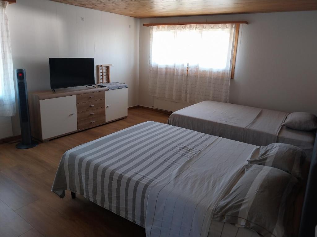 a hotel room with two beds and a television at 1 Zimmer Unterkunft in Spiez