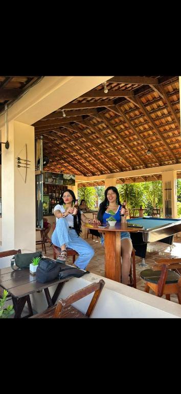 two women sitting in a room with a pool table at The Mountainstream Lodge in Lethem