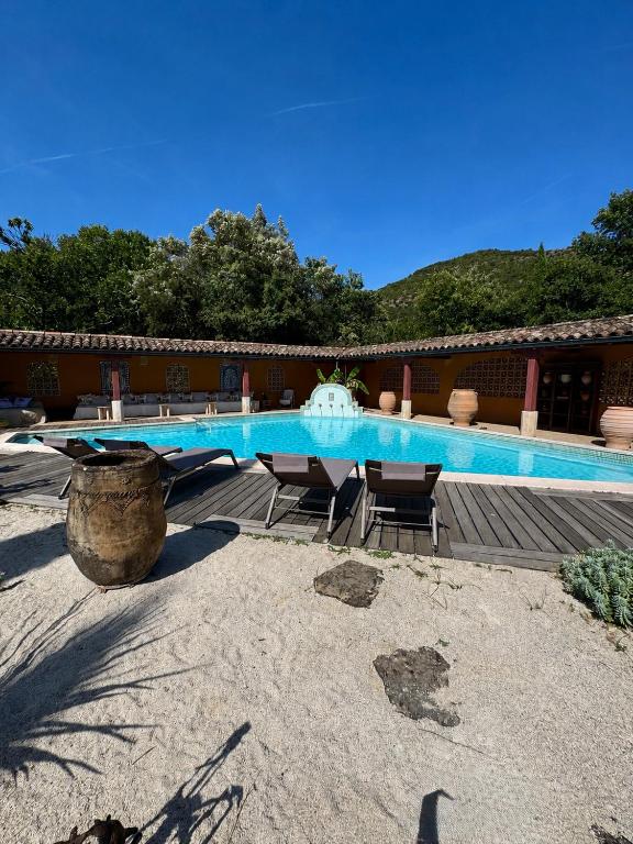a swimming pool with a table and chairs next to a building at L'Hacienda in Mialet