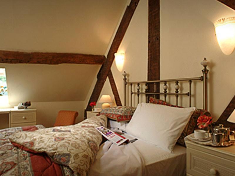 a bedroom with a bed and a desk with a lamp at Gaskell Arms in Much Wenlock