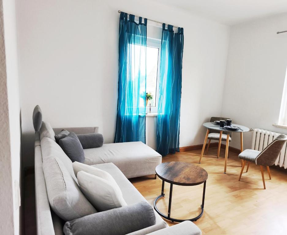 a living room with a white couch and blue curtains at FeWo Dresden-Hellerau in Dresden