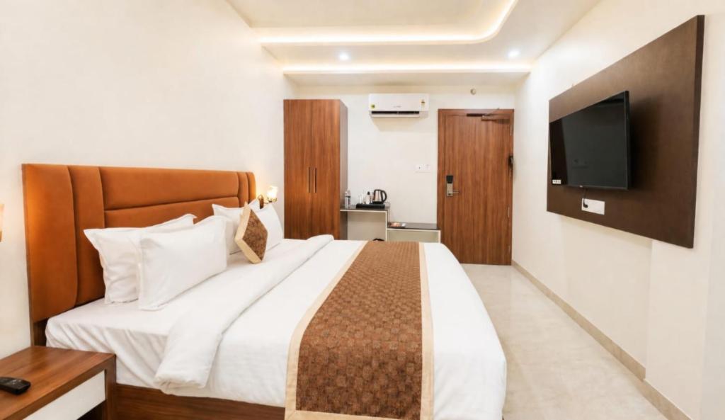 a bedroom with a large bed with a tv on the wall at Hotel Sanidhyam Bliss in Varanasi
