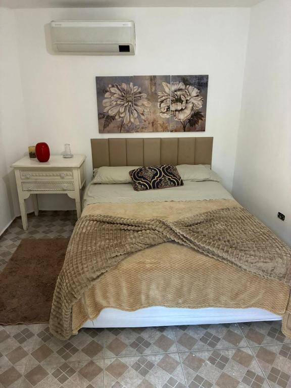 a bedroom with a bed with a blanket and a table at Quarto próximo ao Lago do Major in Atibaia