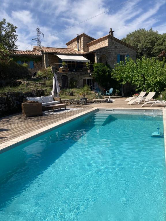 a large blue swimming pool in front of a house at Idyllic Roulotte in Les Assions
