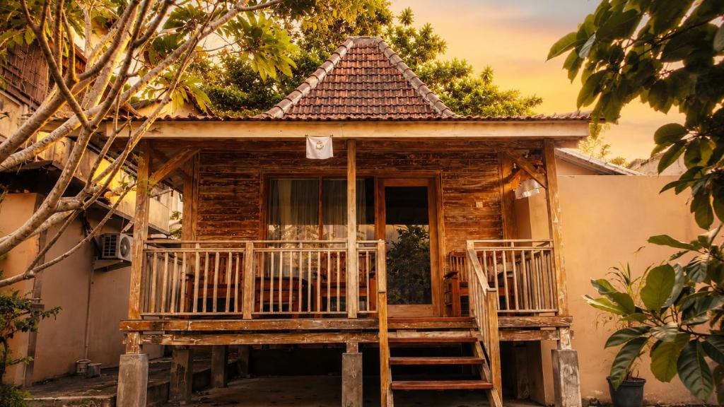 a wooden house with a porch and a door at Indraprastha 2 Bungalow in Ubud