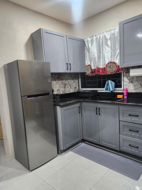 a kitchen with a stainless steel refrigerator and white cabinets at K&C RENTALs in Mount Gay
