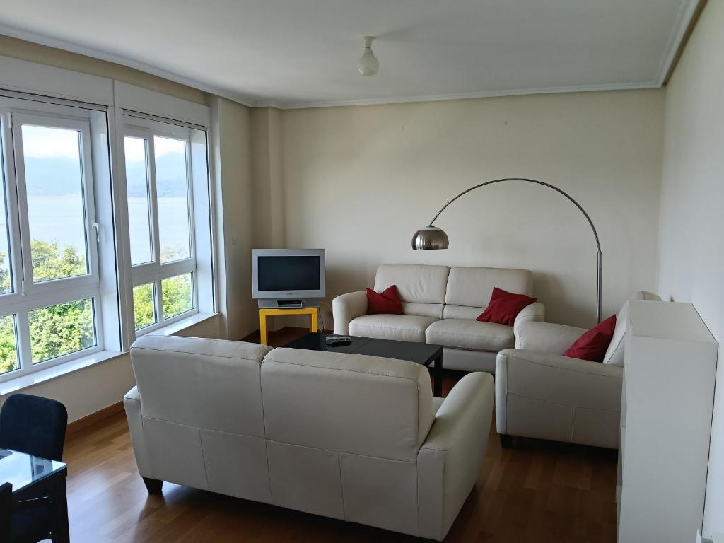 a living room with two white couches and a tv at Casa Vistas in Santa Marta de Ortigueira