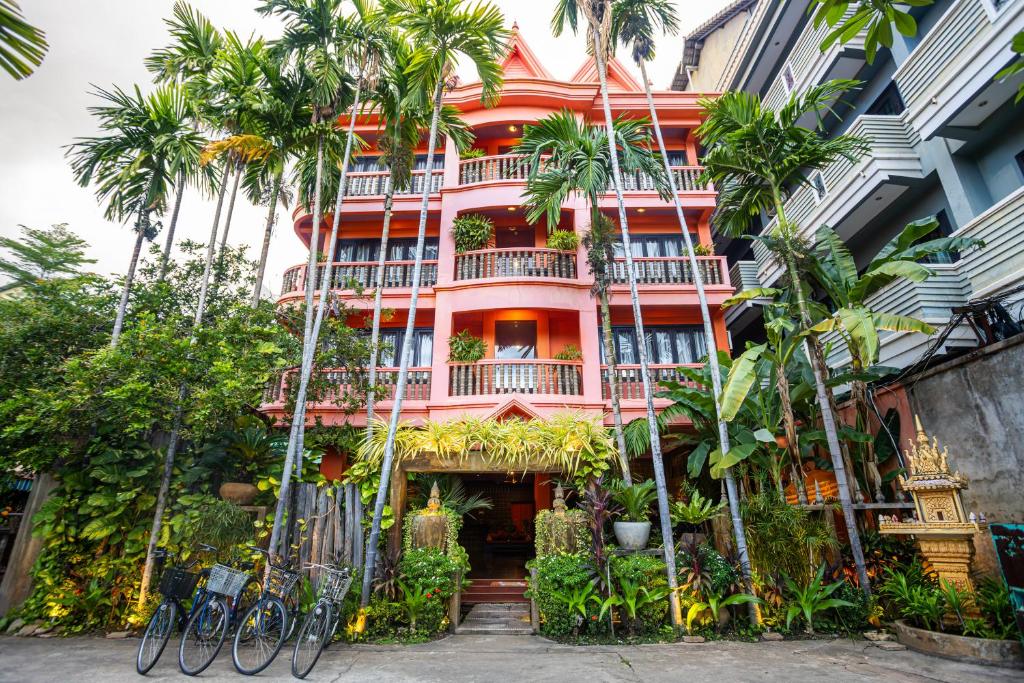 a pink building with palm trees in front of it at Golden Butterfly Villa in Siem Reap