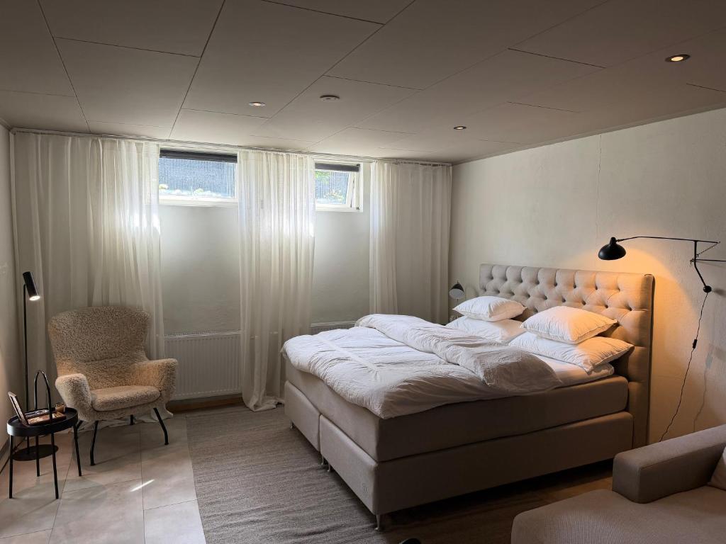 a bedroom with a large bed and a chair at The Cozy Nook - Modern scandinavisk Studio in Kristianstad
