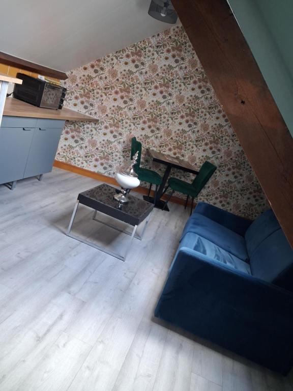a living room with a blue couch and a table at Chez Cosette, studio in Montreuil-sur-Mer