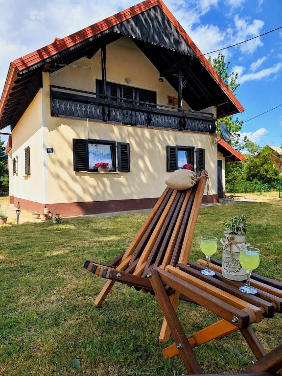 a wooden bench sitting in the grass in front of a house at Kuća za odmor Lipa Dora near Plitvice in Donji Babin Potok