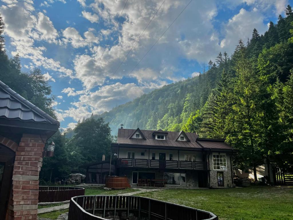 ein altes Haus mit einem Berg im Hintergrund in der Unterkunft Mountain FIsh in Bicaz