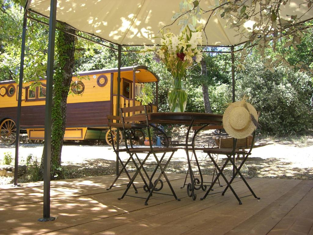 a table and chairs under a tent with a train at Rêve de roulotte in Apt