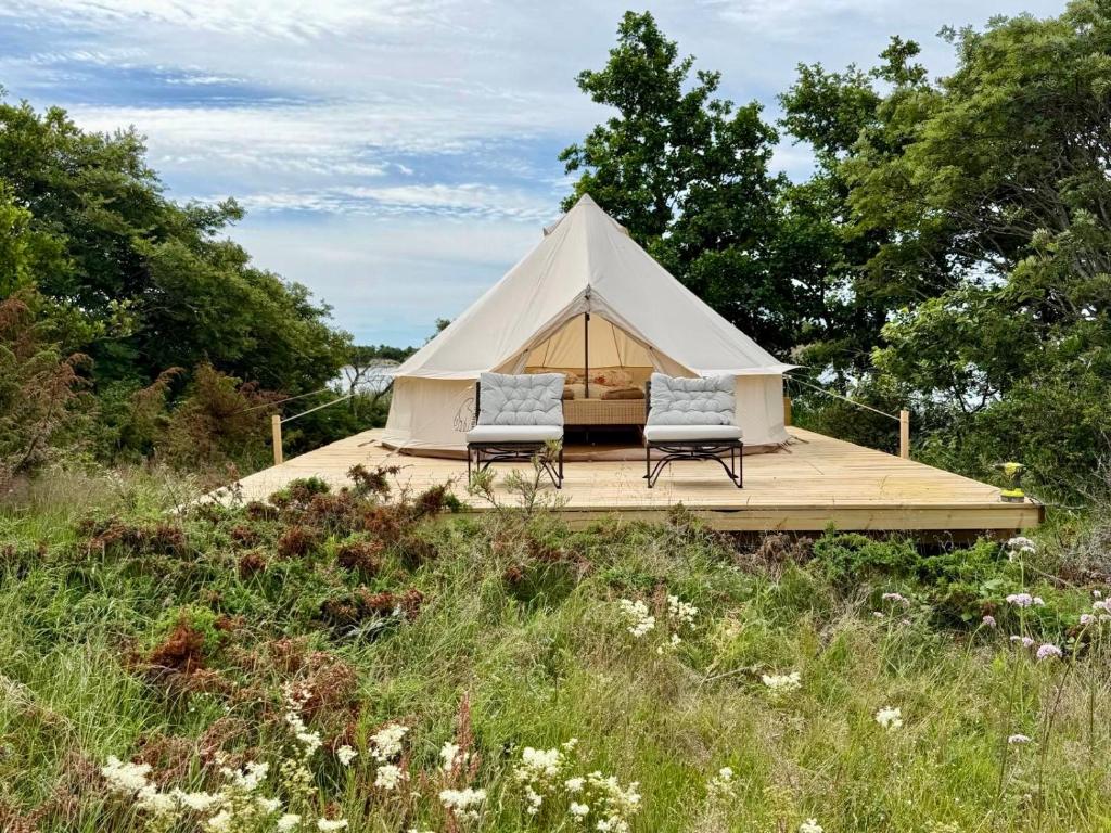 Ein weißes Zelt mit zwei Stühlen auf einer Holzterrasse in der Unterkunft Seglinge Glamping in Norrön