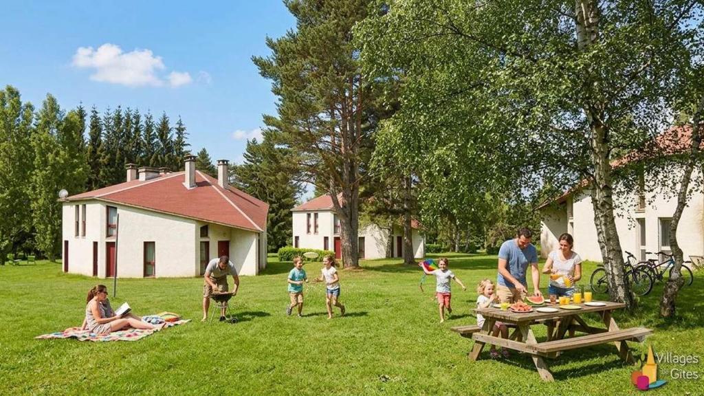 a group of people standing around a picnic table in a yard at Les Gîtes du Bois de Chelles in La Chapelle-Geneste