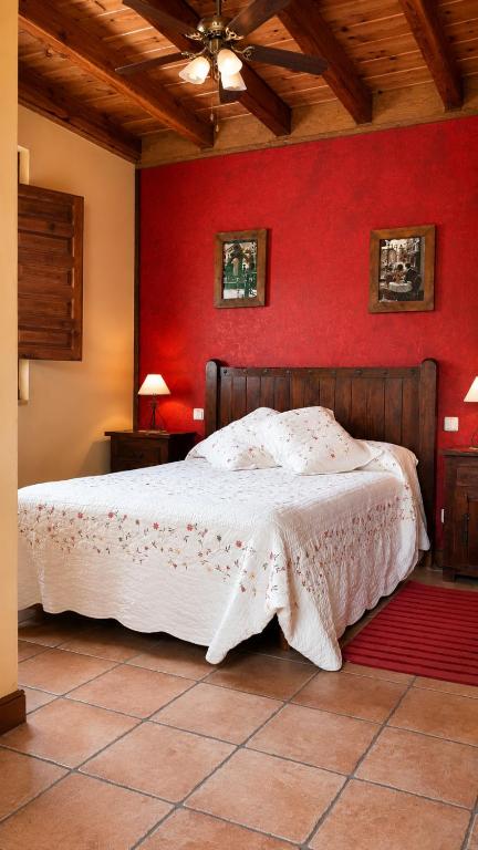 a bedroom with a bed with a red wall at Posada La Vieja Escuela Valles Pasiegos in San Roque de Ríomiera