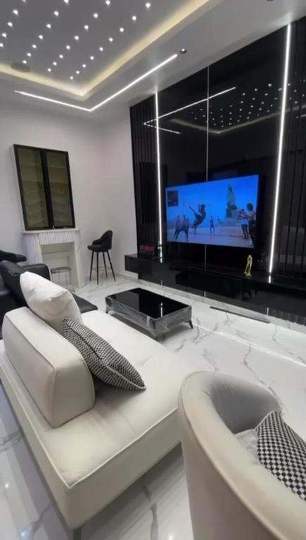 a living room with a white couch and a tv at Greenwich Garden in Onisigun