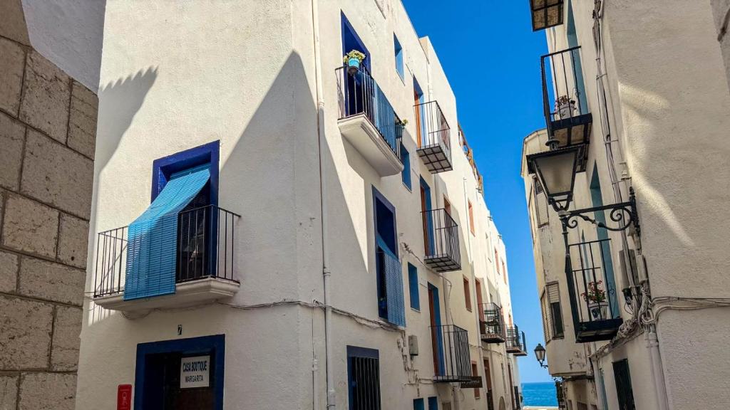 a white building with blue windows and balconies on a street at Casa Boutique Margarita in Peniscola