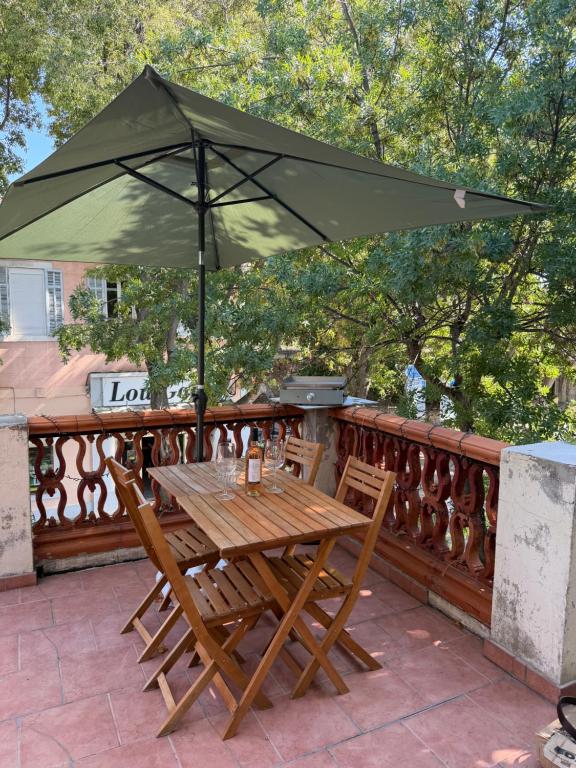 a wooden table and chairs under an umbrella at Appartement SUZANNE in Saint-Cyr-sur-Mer