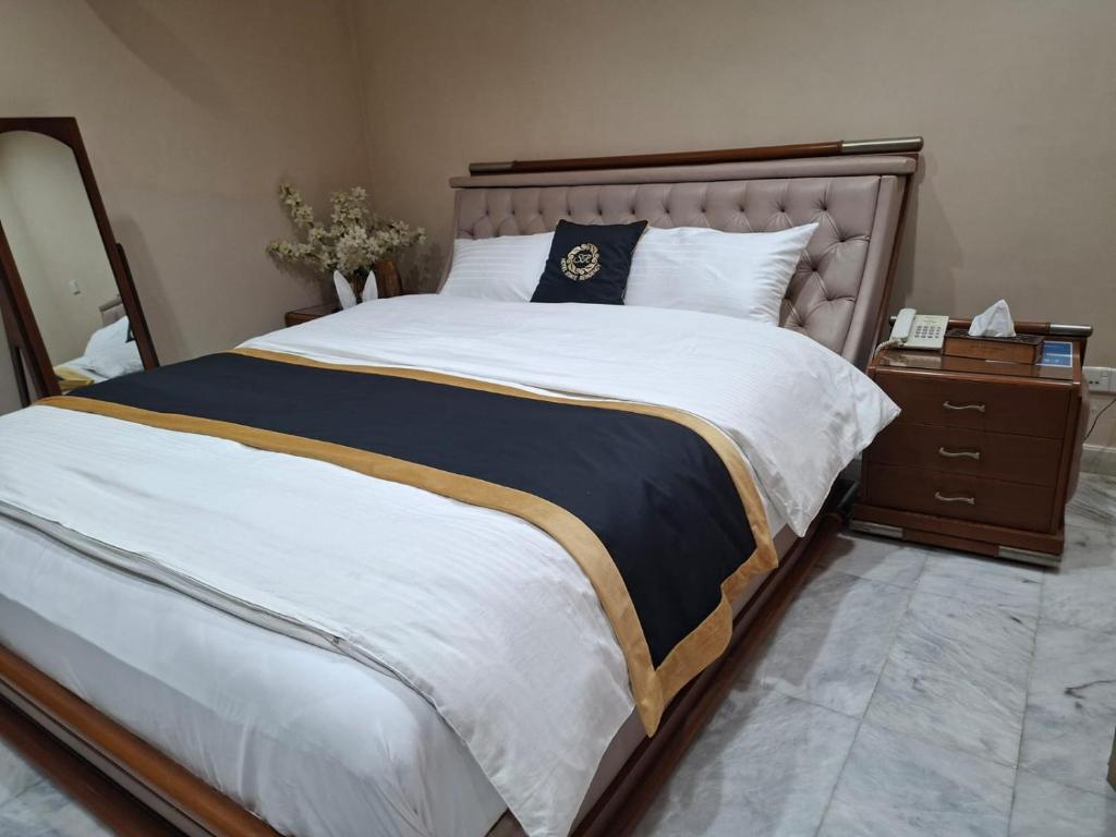 a bedroom with a large bed and a night stand at HOTEL STATE RESIDENCY in Bahawalpur
