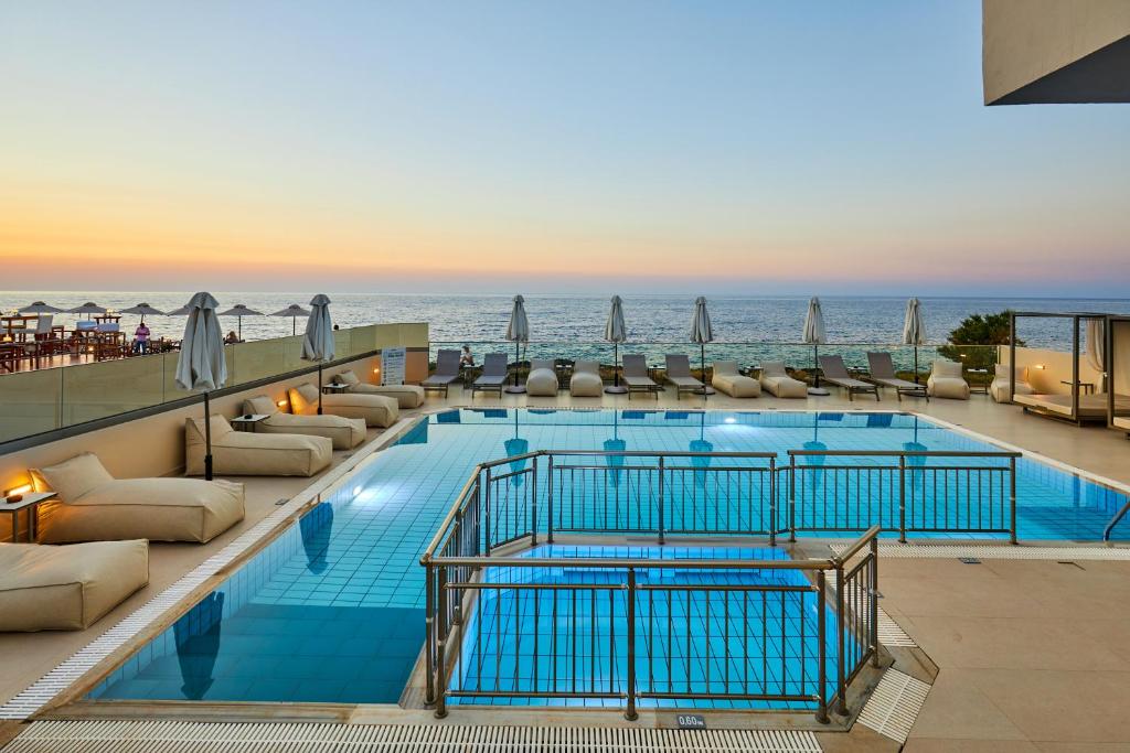 a hotel swimming pool with a view of the ocean at Mila Sissi Bay Hotel in Sisi