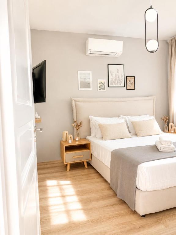 a white bedroom with a bed and a television at NŌSSA Boutique Apartment in Naousa