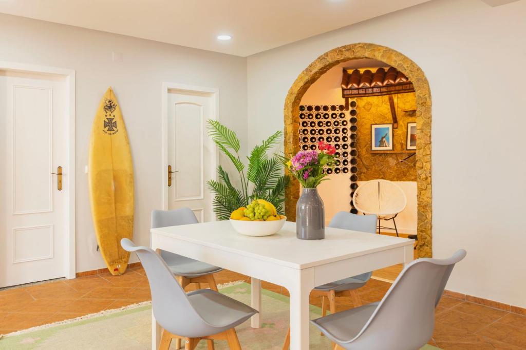 a dining room with a table and chairs and a surfboard at Casa Limão in Charneca