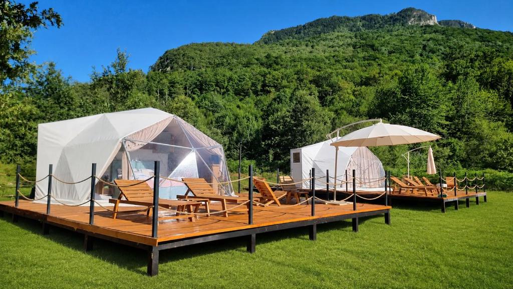 two tents on a deck with chairs and umbrellas at Sutjeska Glamping Domes in Tjentište