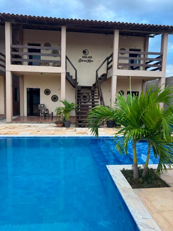 a villa with a swimming pool in front of a house at Solar DorisMar in Luis Correia