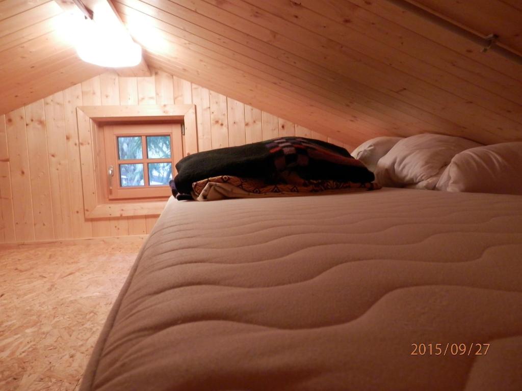 uma cama num quarto com uma parede de madeira em Schalale em Kanzelhöhe