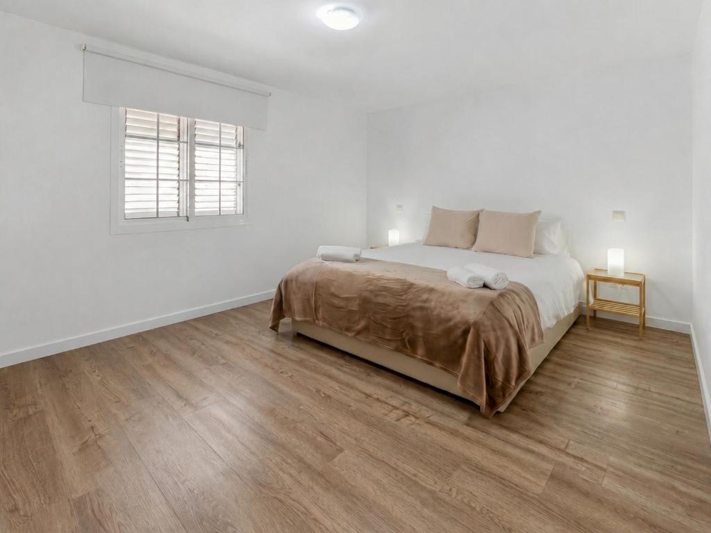 a white bedroom with a bed and a window at Sardina Beach Retreat in Gáldar