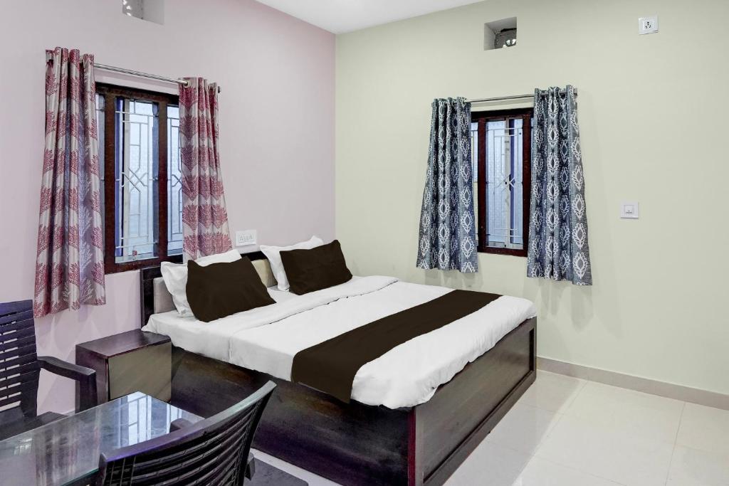 a bedroom with a bed and a table and windows at Hotel O Candel Light Inn in Bhubaneshwar