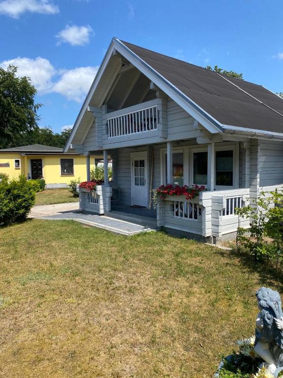 a house with a porch and flowers in the yard at Haus der Sinne in Buddenhagen