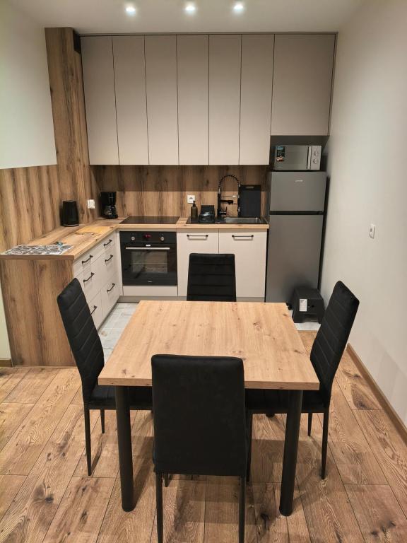 a kitchen with a wooden table and chairs at Apartament Matki Polki II in Łódź