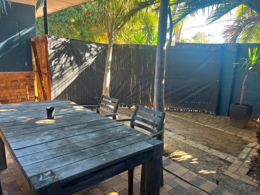 a wooden table with two chairs and a fence at Blue Moon Guest Rooms in Bellville
