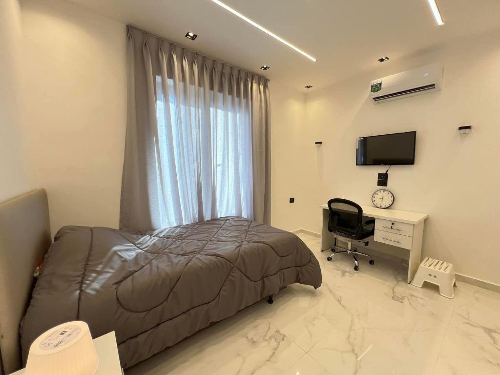 a bedroom with a bed and a desk and a television at Bader home in Cairo
