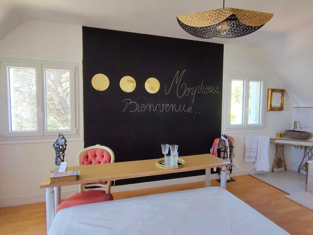 a dining room with a table and a black wall at Morphoses, Maison de créatrice & parc privé près de Chenonceaux in Chissay-en-Touraine