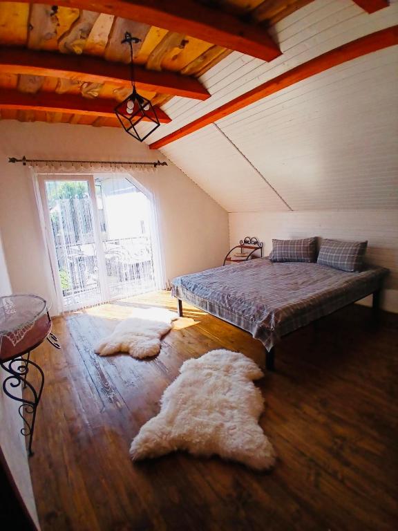 a bedroom with a bed and two rugs on the floor at Карпатська Хата in Yasinya