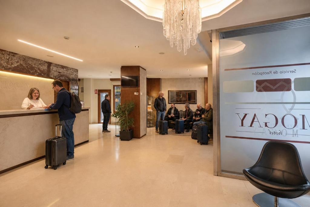 a lobby with people waiting at a counter in a restaurant at Hotel Mogay in Chantada