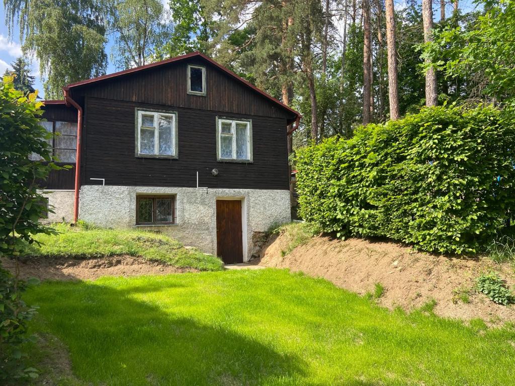 a small black and white house with a door at Chata Slapy Skalice in Slapy