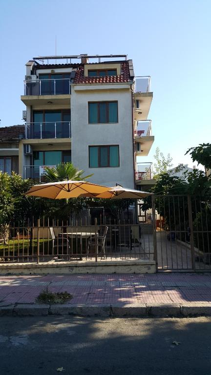 uma cerca com uma mesa e guarda-chuva em frente a um edifício em Guest house Beglik Tash em Primorsko