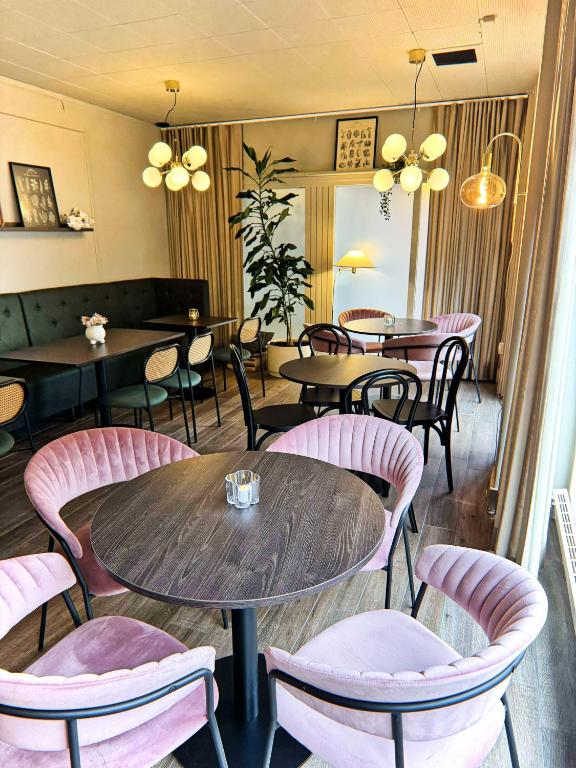 a restaurant with pink chairs and tables and tables at Hotel Amadeus Halmstad in Halmstad