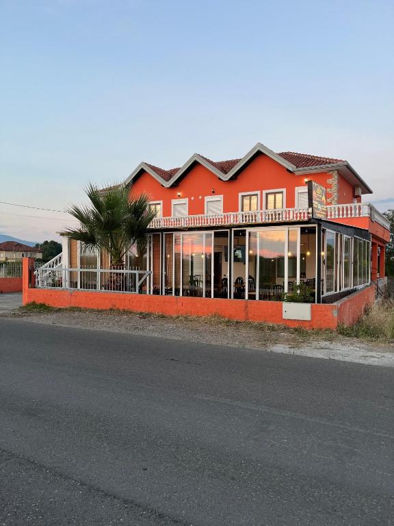 a red building with a palm tree in front of it at Zefi Grill House in Lezhë