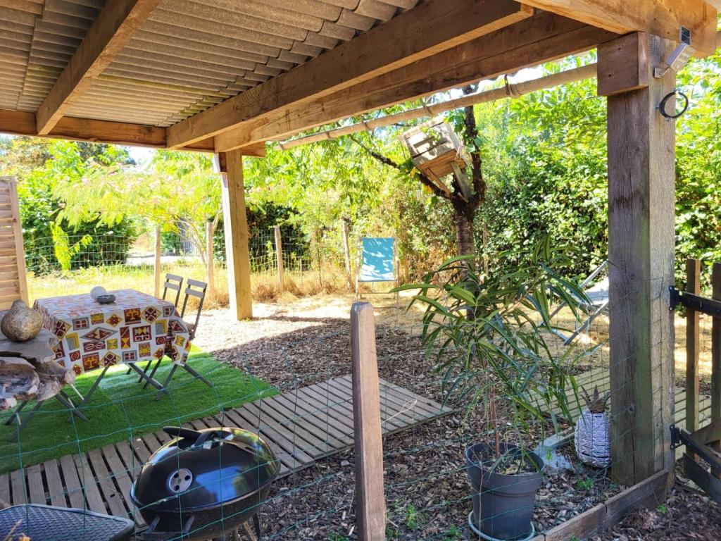 a wooden pergola with a table at Maisonnette cosy au calme avec jardin clos - Puy dufou in La Ronde
