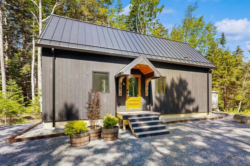 a small house with a yellow door and some plants at Charming New Home with Hot Tub, Spacious Deck, Gas Grill, WiFi, and Washer/Dryer in Boothbay
