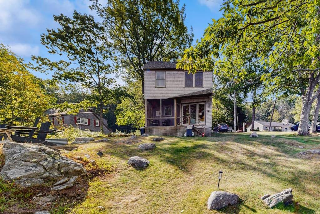 a house on a hill with rocks in the yard at Waterfront Paradise with Dock, Big Yard, Sundeck & Epic Bay Views | Dog-Friendly in Boothbay